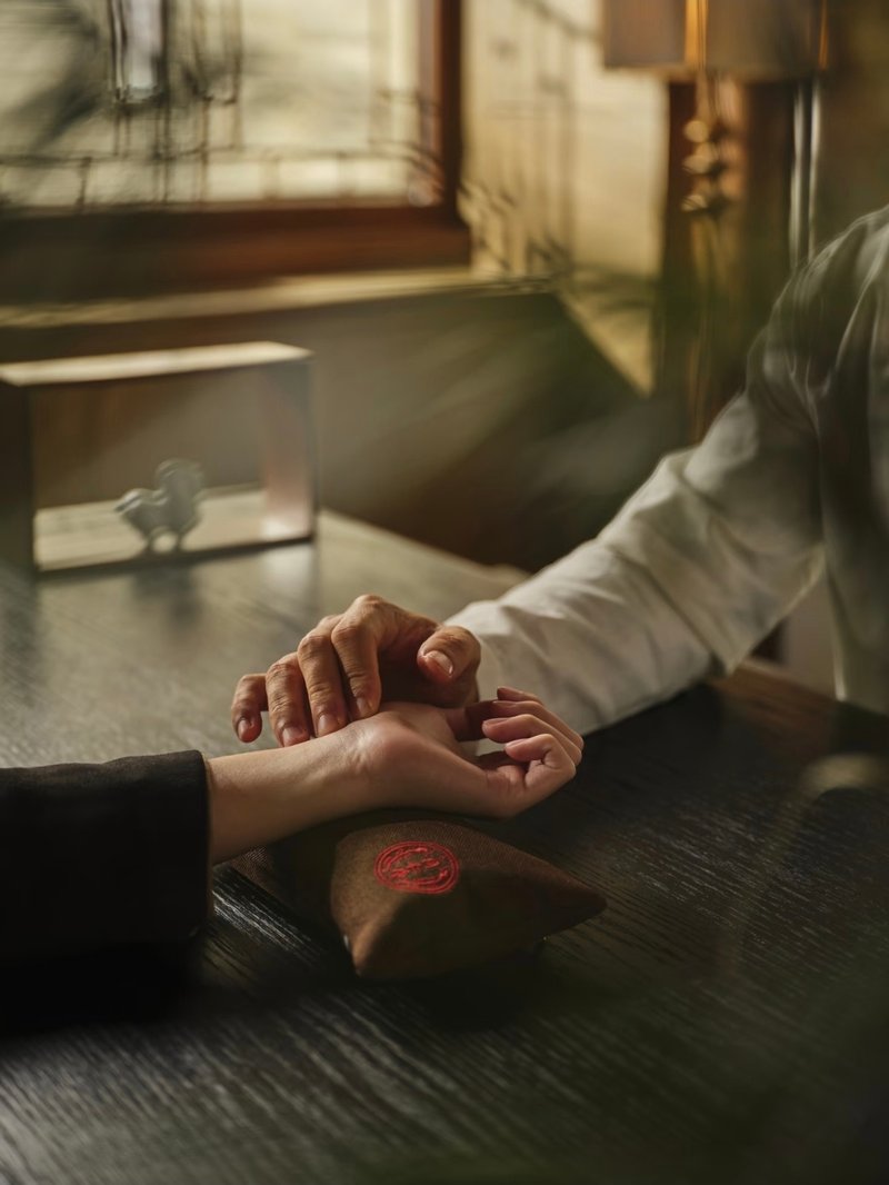 A physician taking a pulse reading beside a wax-sealed pouch