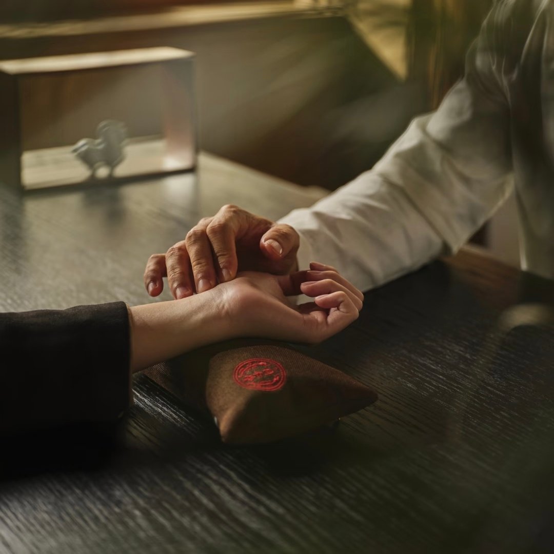 A physician taking a pulse reading beside a wax-sealed pouch, Chengdu