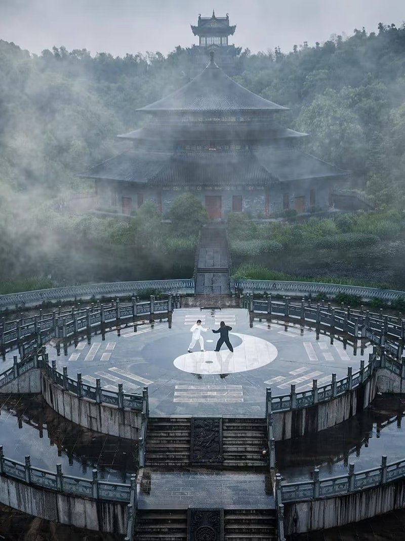 Tai Chi practice on a yin-yang platform in front of a mountain temple